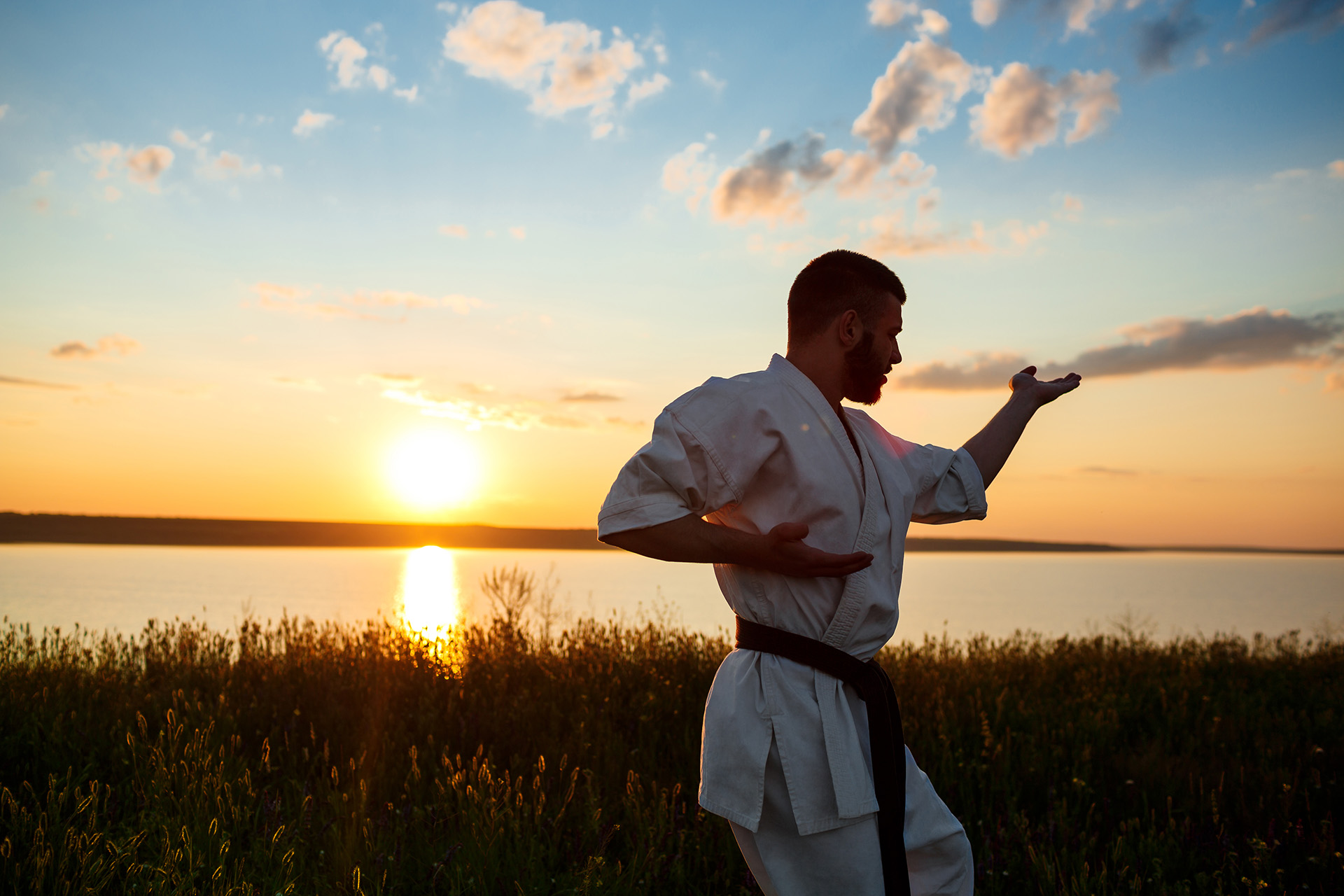 silhouette-of-sportive-man-training-karate-in-field-at-sunrise